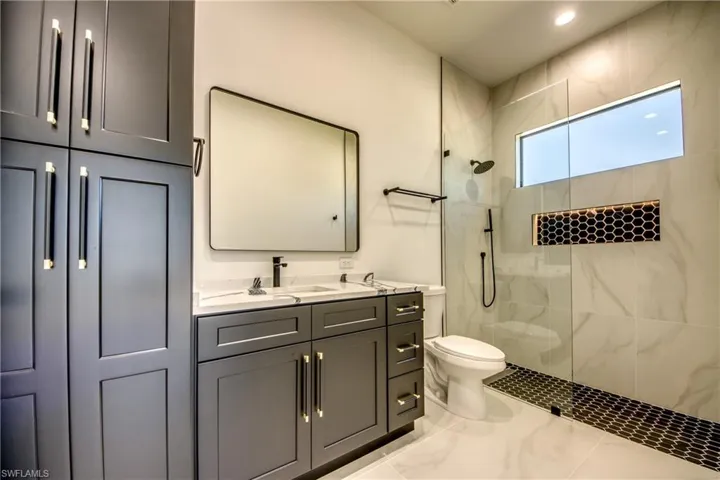 Bathroom with a tile shower, vanity, and toilet