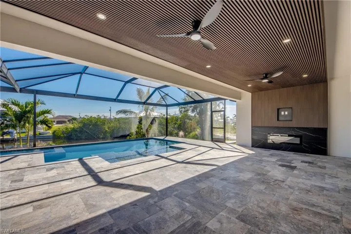 View of swimming pool with a patio, glass enclosure, and ceiling fan