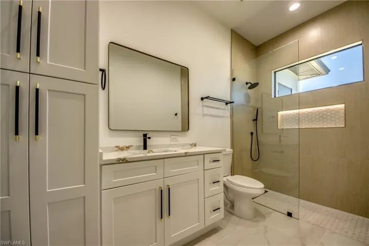 Bathroom with a tile shower, vanity, and toilet