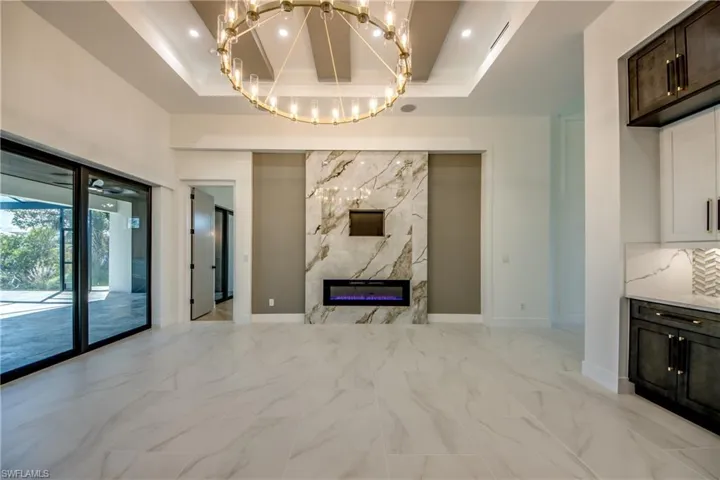 Unfurnished living room featuring a notable chandelier, a tray ceiling, and a premium fireplace