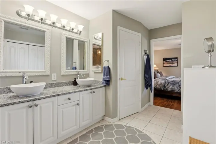 Full bath featuring double vanity, light tile patterned flooring, a closet, and connected bathroom