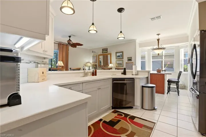 Kitchen with hanging light fixtures, dishwashing machine, crown molding, freestanding refrigerator, and white cabinetry