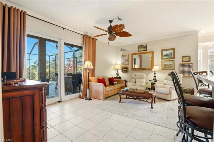Living room with crown molding, plenty of natural light, light tile patterned flooring, and a ceiling fan