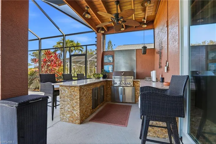 View of patio featuring exterior kitchen, a lanai, a sunroom, and a ceiling fan