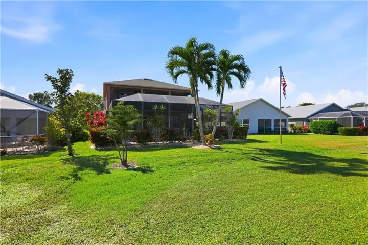 Back of property featuring glass enclosure, a sunroom, and a yard