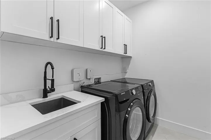Laundry room with baseboards, a sink, cabinet space, and washing machine and dryer