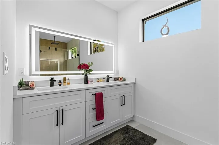 Bathroom featuring double vanity, a sink, a shower with door, and a wealth of natural light