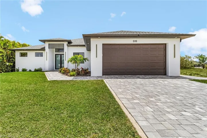 Prairie-style house featuring a front yard, decorative driveway, stucco siding, french doors, and an attached garage
