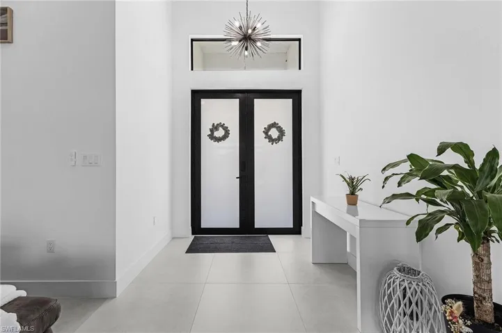 Entryway with baseboards, a notable chandelier, and light tile patterned floors
