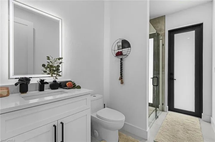 Bathroom with toilet, a shower stall, tile patterned flooring, and vanity