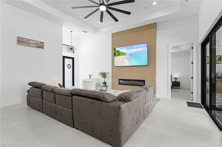 Living area with a raised ceiling, ceiling fan, a towering ceiling, and a fireplace