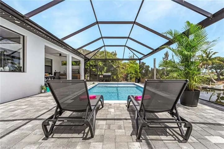 Pool featuring a ceiling fan, glass enclosure, and a patio area
