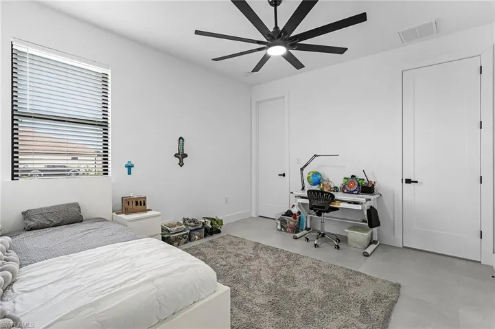 Bedroom with ceiling fan, concrete flooring, and visible vents