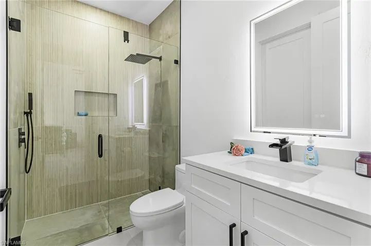 Bathroom with vanity, toilet, tile patterned flooring, and a stall shower