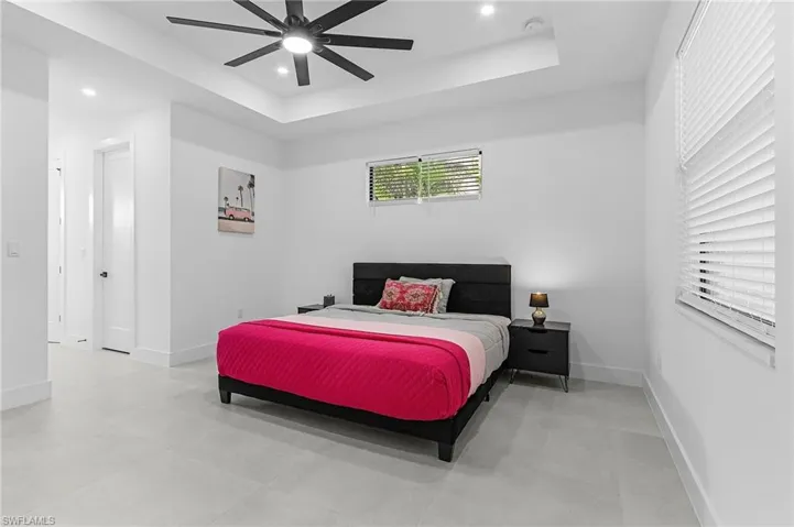 Bedroom featuring a raised ceiling, baseboards, and recessed lighting
