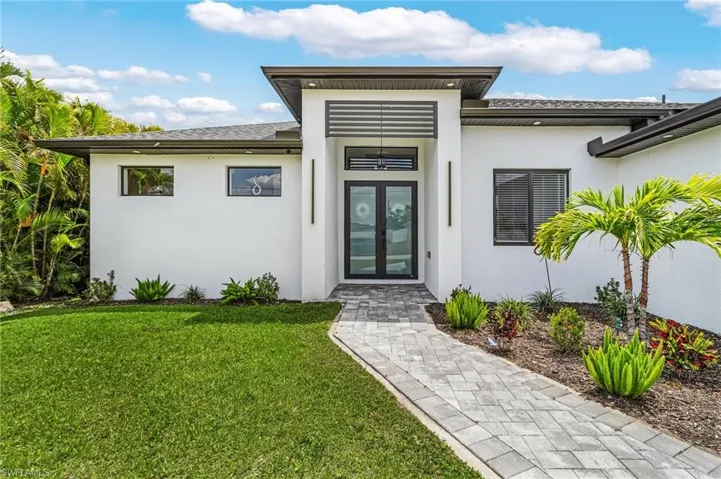 Property entrance with french doors, stucco siding, and a yard
