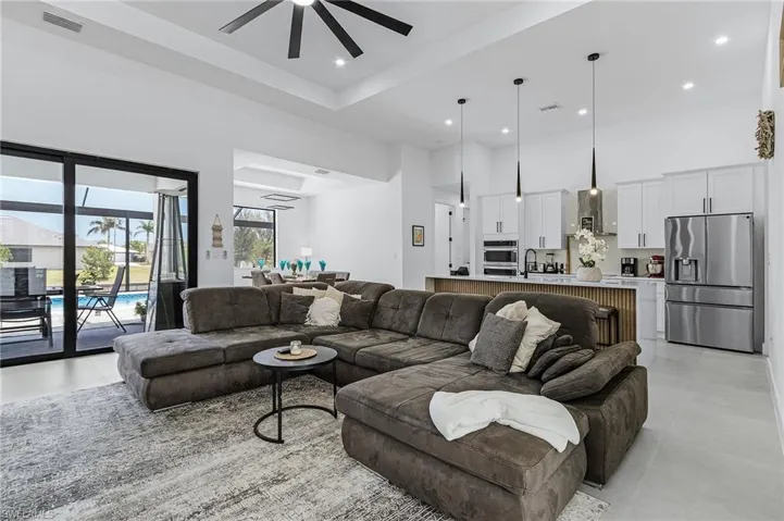 Living room featuring light tile patterned floors, a high ceiling, a ceiling fan, and visible vents