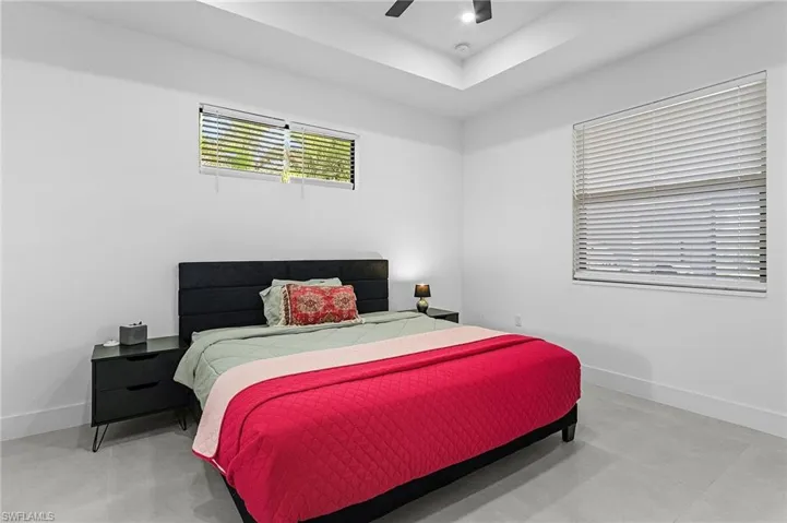 Bedroom with baseboards, a ceiling fan, and finished concrete flooring