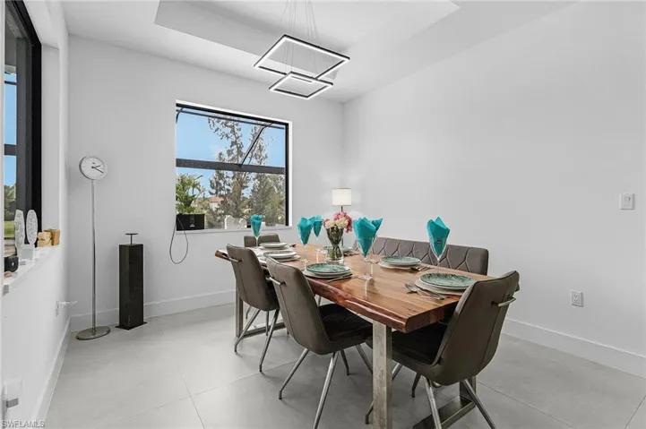 Dining room with baseboards, a tray ceiling, and a notable chandelier