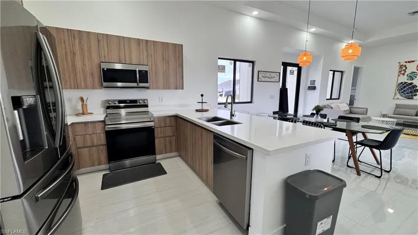 Kitchen featuring appliances with stainless steel finishes, modern cabinets, open floor plan, pendant lighting, and recessed lighting