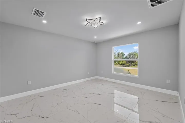 Spacious room featuring large format tile flooring, a prominent window with a white frame, recessed lighting, and a decorative flush-mount ceiling fixture