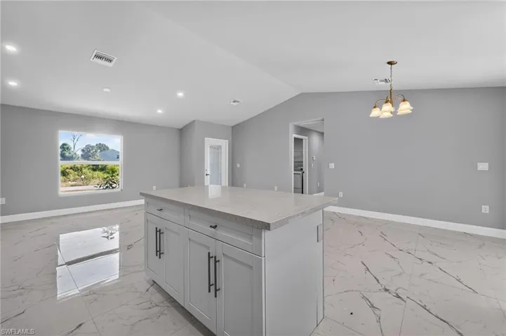 Central kitchen island featuring a light gray countertop, light gray cabinetry, and matte black hardware