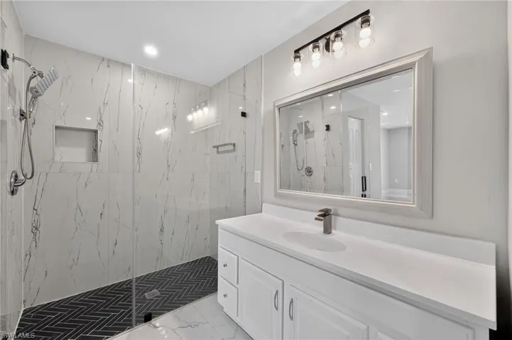 Contemporary bathroom featuring a spacious walk-in shower with clear glass enclosure and black herringbone tile floor