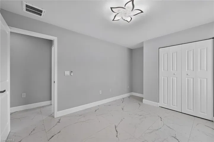 Room featuring large format tile flooring with veining, light gray painted walls, and white baseboards