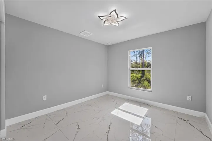 Room featuring large format marble-look tile flooring, light gray wall paint, and white trim