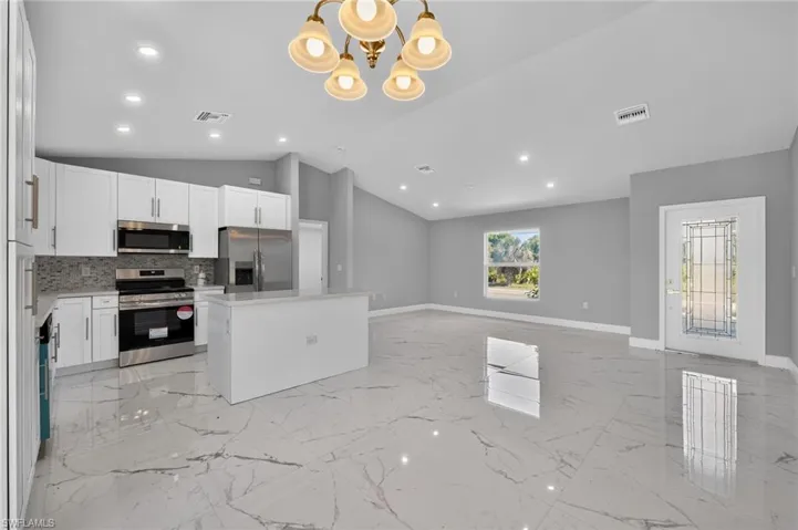 Open-concept living area featuring a kitchen with white cabinetry, stainless steel appliances, and a central island