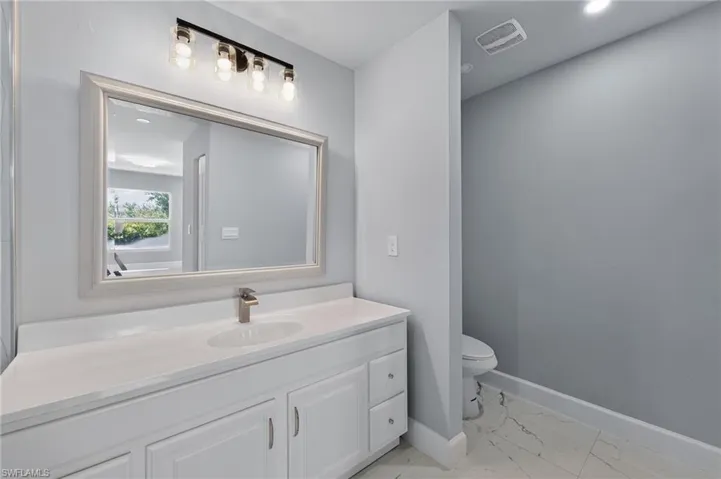 Bathroom vanity featuring a framed mirror, a five-light fixture, and a single basin sink with a brushed nickel faucet