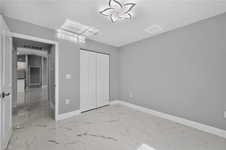 Room featuring large format white tile flooring with gray veining, light gray walls, and white baseboards