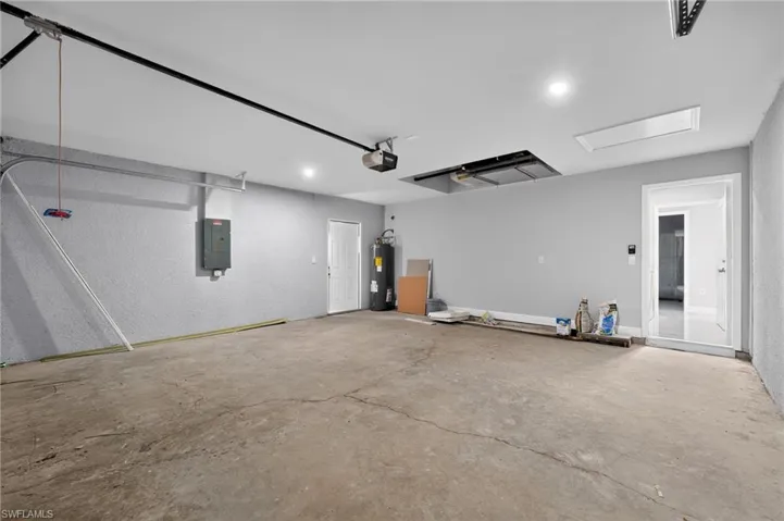 Spacious garage featuring a concrete floor, recessed lighting, white walls, and an overhead garage door mechanism