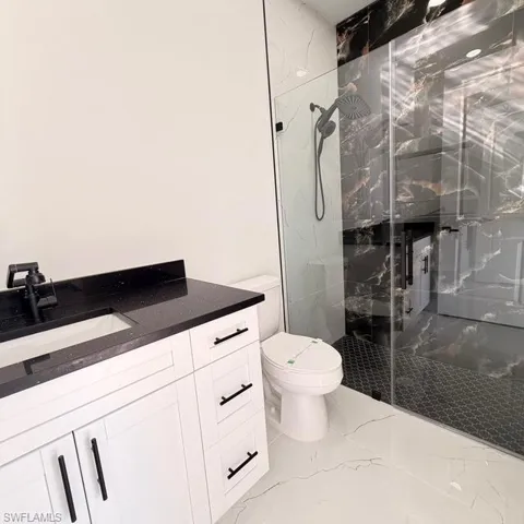Full bathroom with a marble finish shower, vanity, and light marble finish floors