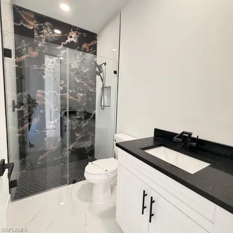 Full bathroom with vanity, a marble finish shower, marble finish flooring, and recessed lighting