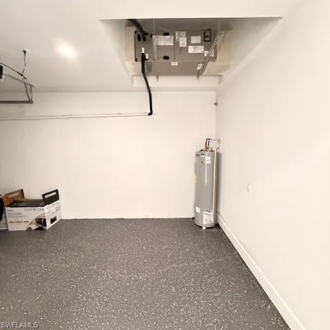 Garage featuring baseboards and electric water heater
