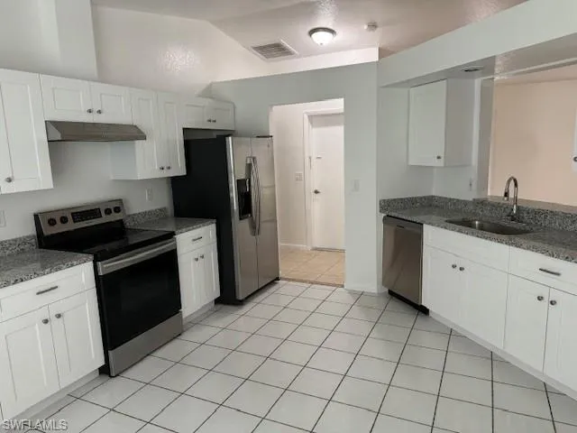 Kitchen featuring stainless steel appliances, white cabinets, sink, and light tile floors