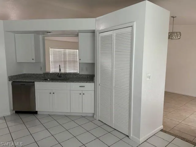Kitchen featuring white cabinetry, sink, stainless steel, pantry dishwasher, and light tile floors