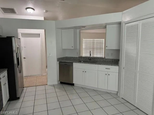 Kitchen with light tile floors, white cabinetry, appliances with stainless steel finishes, sink, and a textured ceiling