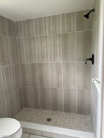 Bathroom with tile floors, tiled shower, and toilet