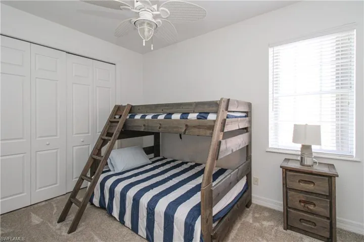 Carpeted bedroom featuring a closet and ceiling fan