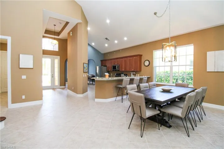 Dining area with an inviting chandelier, light tile patterned floors, and high vaulted ceiling