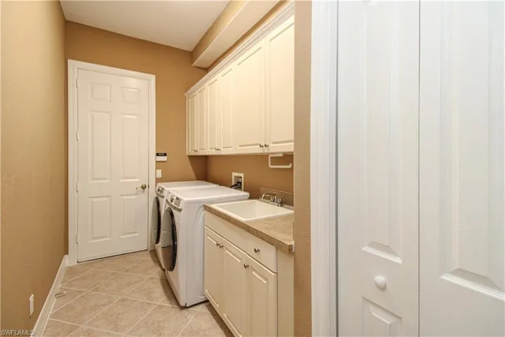 Laundry area featuring sink, cabinets, washer and dryer, and light tile patterned floors