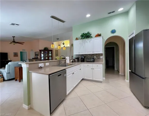 Kitchen with sink, stainless steel fridge, black dishwasher, kitchen peninsula, and newly updated white cabinets