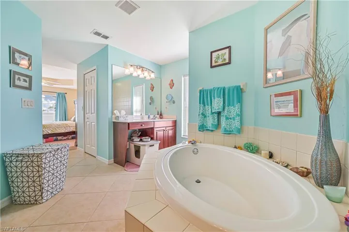 Bathroom featuring tile patterned floors, vanity, and tiled tub