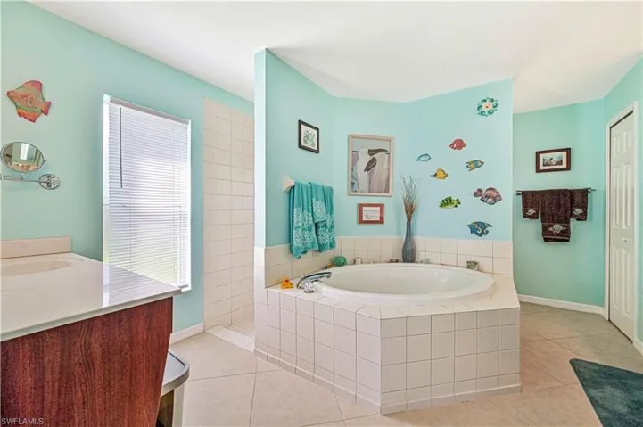 Bathroom with tile flooring, vanity, walk around shower for two surrounding a relaxing tiled tub