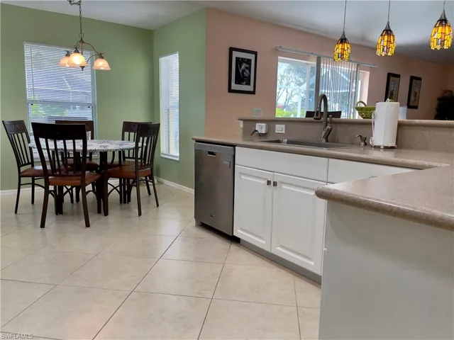 Kitchen featuring sink, hanging light fixtures, light tile patterned floors, dishwasher, and Newly updated white cabinets