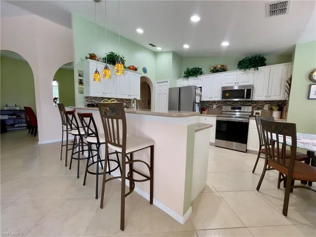 Kitchen featuring appliances with stainless steel finishes, decorative light fixtures, a breakfast bar, and Newly updated white cabinets