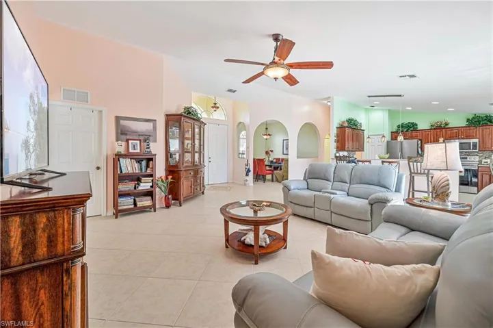 Tiled living room with lofted ceiling and ceiling fan