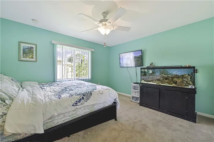 Carpeted bedroom featuring ceiling fanand closet
